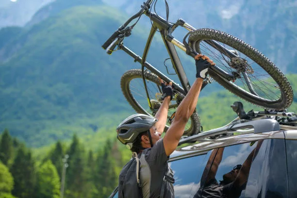 a man placing bicyle in the suv roof rack