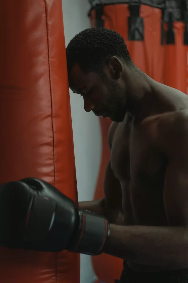 man practicing boxing holding the punching bag 